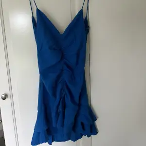 Jag säljer denna blåa klänning från zara. Den har fina detaljer på framsidan och öppen i ryggen med en snörning och en resor nertill. 
