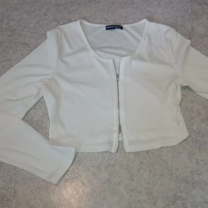 Topp dubbeländad dragkedja vit - Vit sommartopp med dubbeländad dragkedja, långärmad