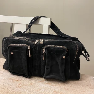 Nunoo väska - Nunoo väska i modellen: Helena New Suede - Axelremsväska. Svart med silverdetaljer. I väldigt gott skick. 