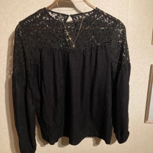 Långärmad tröja - Svart långärmad tröja med spets upptill. Den är i behagligt viskosmaterial.   Normal strl 38 