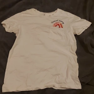 T-shirt  - T-shirt med tryck och pärlor över bröstfickan 