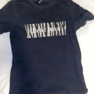 Säljer en svart T-shirt med zebratryck. På tröjan står det ”Fearless”, från ginatricot i storlek S. Knappt använd. OBS: köparen står för frakten. (Annonsen finns ute på fler sidor.)