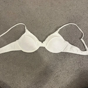 Bikini topp - En vit bikini topp med fint mönster och volang upptill. Aldrig använd pga för liten