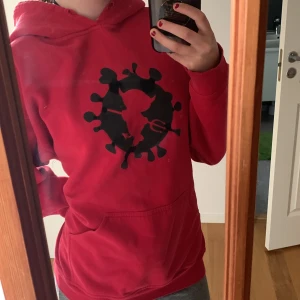Röd hoodie med tryck  - En använd hoodie i bra skick. Lite skada längst ner på ärmen men är inget man ser, förutom det har den inga defekter. Be om bild i fall man vill se.  Passa på nu när det är gratis frakt på alla hoodies på fredag! 