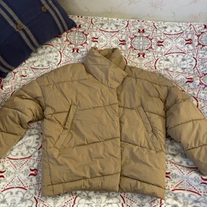 Beige pufferjacka - Storlek XS, från Bikbok. Inte använd. Finns i Eskilstuna annars står köparen för frakten.