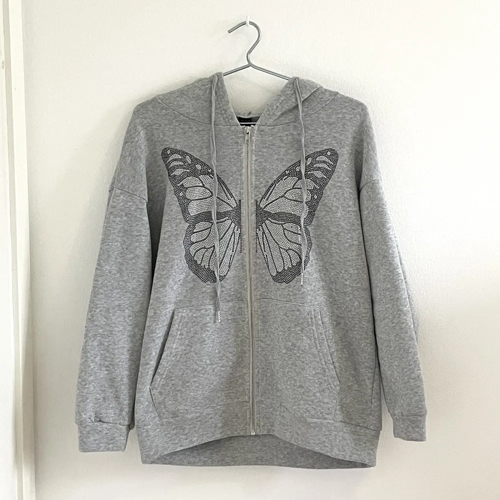 Populär grå zip up hoodie från shein med en fjäril på. Använd få gånger, inga defekter och är i nyskick. Köpt för 219kr men säljer för 50kr.. Hoodies.