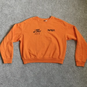 Collegetröja orange - En supersnygg och skön collegetröja i orange färg. Har tryck på framsidan och i storlek M från divided. 