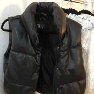 zara väst - Säljer en svart lite glansig puffer väst från zara. Den är knappt använd och är i ett bra skick. Skriv gärna för fler frågor💓