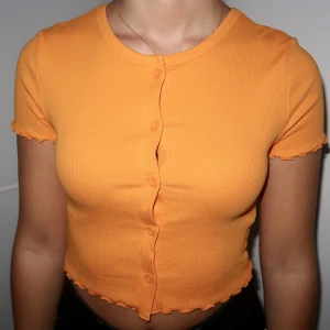 Orange kortärmad topp med knappar fram - Aldrig använd. 