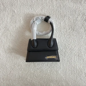 KOPIA svart jacquemus väska  - En väldigt fin KOPIA på denna fina jacquemus väskan, aldrig använd och dustbag följer med! Kan tänka mig att gå ner i pris! (Den har även ett axelband så att man kan hänga den runt axeln) 