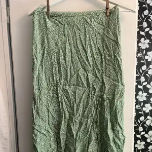 Somrig kjol från HM med slit på sidan och dragkedja.  Färgerna på den är grönt och vitt.  Använd ett fåtal gånger men i mycket gott skick. Storlek M. Längden på den är midi, den går till mitten av vaden på mig som är 170cm.