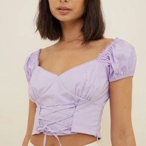 Lila topp - Säljer denna lila topp med puffärmar och snörningsdetaljer, då den blivit för liten. Från Misslisibells kollektion med NAKD. Toppen är aldrig använd så den är i nyskick! DM för fler frågor ❤️‍🔥 Nypris 349:-