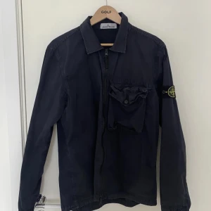 Stone island overshirt - Overshirt från Stone Island i storlek L i bra skick, endast solblekt. Passar M, köpt från Nk och den går igen verifieringen om äkthet. Perfekt till sommarkvällar, för mer frågor eller funderingar kom pm!