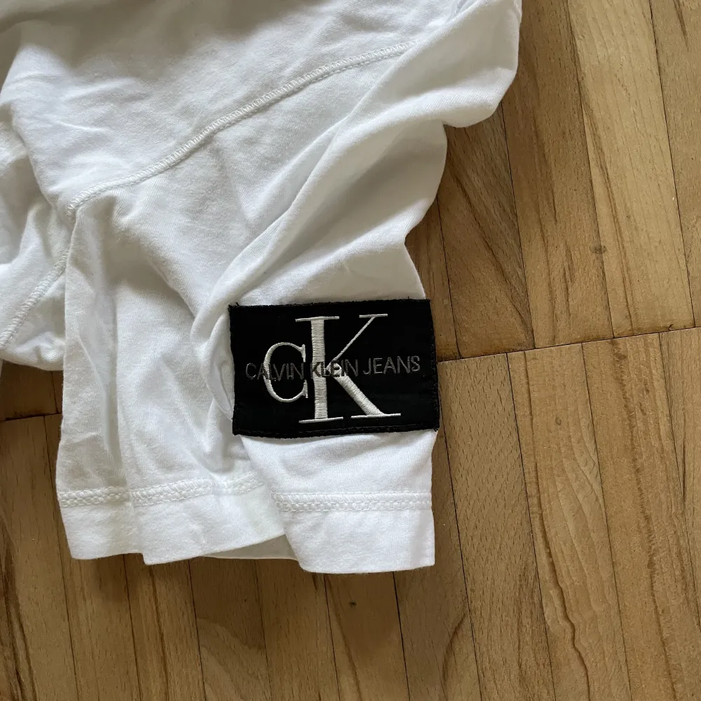 Calvin Klein Jeans T-shirt med en loggad patch på vänster arm.  Köpt för 450kr på Calvin Klein Köparen står även för frakten!. T-shirts.