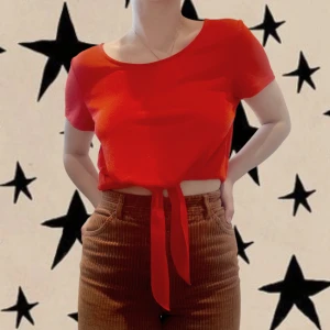 Röd sommrig topp - Somrig röd t-shirt (icsh) av tunnt elastiskt tyg. Går att knyta längst ner men också fin att bara stoppa ner i byxorna. Funkar till vardags och mer formellt. 95% polyester 5% elastan