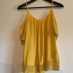 Gul tröja  - Gul tröja från Pigalle med smala axelremmar, och korta ärmar som hänger nerför armarna. Storlek 34 men passar absolut även 36. 
