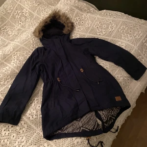 Vinterjacka i parkasmodell M/L - Lite längre marinblå vinterjacka i fint skick. Märkt med L men lite liten i storlek så mer mot en stor M. 