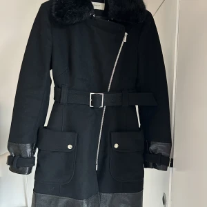Karen Millen kappa - Karen Millen kappa, svart med avtagbar fuskpälskrage. Skärp med fickor, silverfärgade knappar med logga. Fint skick, stl M