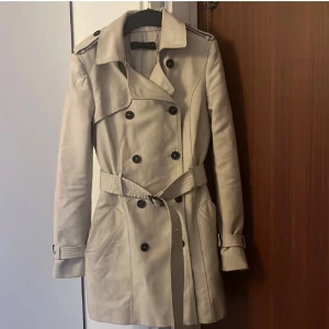 Trenchcoat zara - Trenchcoat från zara storlek xs. Har en defekt på tygets insida som jag sytt ihop, detta syns inte alls! Men skickar gärna bild på det ☺️ Annars bra skick