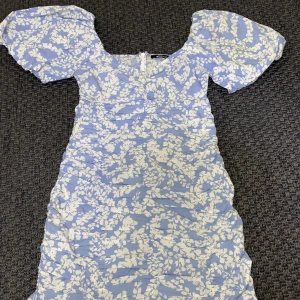 Sommarklänning  - Blommig klänning från Gina tricot. Blommig klänning från Gina Tricot. Endast använd en gång för skolavslutnigen. Puffiga armar men lite hård material. 