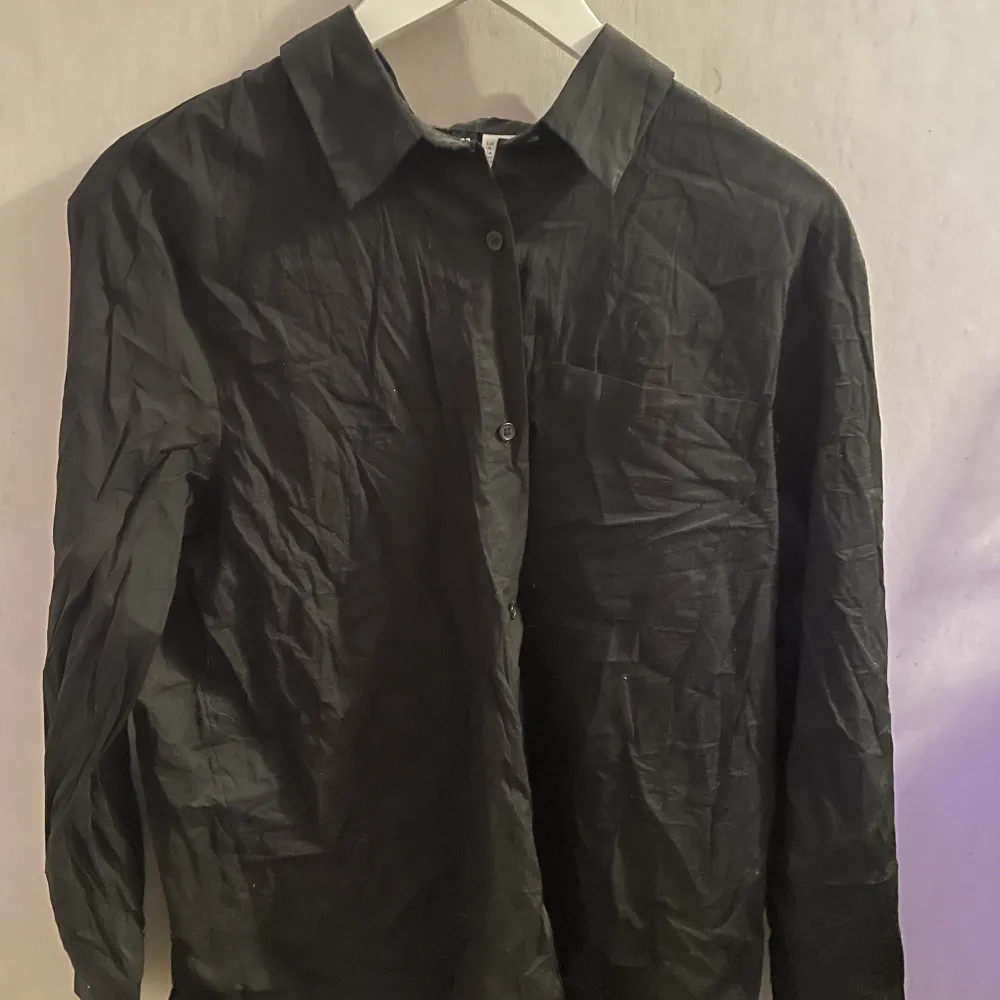En svart skjorta från HM. Köpte den som oversize men skulle inte säga att den är de på mig längre och därför jag säljer den🥰. Paidat.
