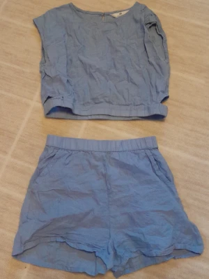 Ljusblått sett - Säljer ett ljusblått sett från H&M i mjuk bomull. En topp samt shorts till. Toppen har en öppen "ficka" på båda sidorna. Går att öppna och knäppa i nacken. Stl 152.    !!endast swish +frakt!!