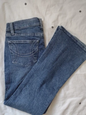 ultra low bootcut jeans - Säljer ett par blå ultra low bootcut jeans från Gina Tricot i storlek 38. Jeansen har klassisk femficksdesign, snygga kontrastsömmar på bakfickorna och låg midja. Materialet är jeans i en djupblå tvätt. 