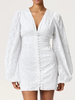 Vit blommig kortklänning från Adoore - Supersöt ny & oanvänd vit kortklänning från Adoore med broderade blommor, v-ringning och långa puffärmar. Klänningen har klädda knappar framtill och är gjord i ett tunt bomullstyg som känns luftigt och fräscht. Perfekt för dig som tar studenten eller till midsommar! Hör av er vid frågor! Säljer då klänningen var för liten för mig! 