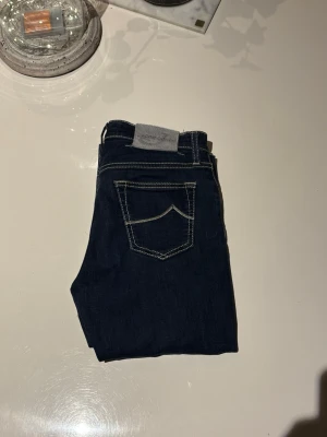 Jacob choën jeans - Beskrivning: Snygga blå jeans i slim fit-modell. Klassisk tvätt som passar till det mesta. Bekväma att bära och sitter bra på benen. Använda men i gott skick, inga hål eller fläckar. Perfekta för vardag, skola eller fest. Jeansen är i storlek W28 och är i modellen 710 slim 