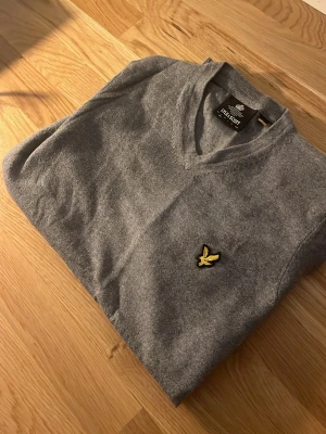 Grå v-ringad tröja från Lyle & Scott - Hej! Nu säljer vi en v-ringad stickad tröja från Lyle&Scott 🟡! Denna tröja är väl använd! 
