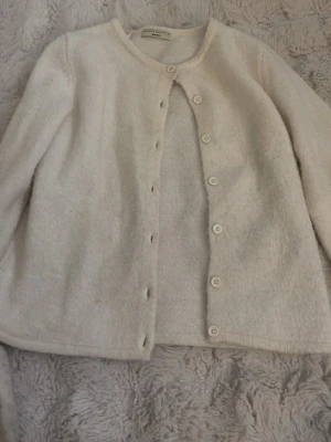 Beige kofta från Gina Tricot XS - Mysig beige kofta från Gina Tricot i premiumkvalitet. Koftan har rund halsringning, långa ärmar och stängs med knappar framtill. Perfekt för lager-på-lager och enkel att matcha med olika outfits.