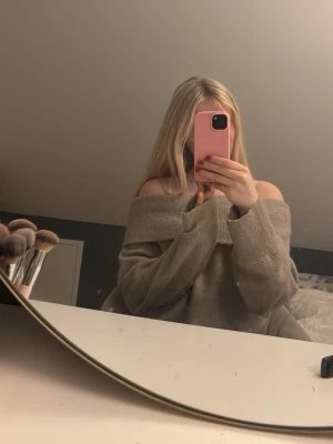 Beige offshoulder stickad tröja - Säljer en supermysig beige stickad tröja med bred offshoulder-ringning. Tröjan har långa ärmar och en oversized passform som ger en chill vibe. Perfekt att slänga på sig när det är lite kyligt ute.