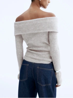 Beige ribbad offshoulder stickad tröja - Superfin beige stickad tröja med ribbad struktur och offshoulder-design. Långärmad och sitter snyggt figurnära. Perfekt att styla med jeans eller kjol för en chill men ändå trendig look.