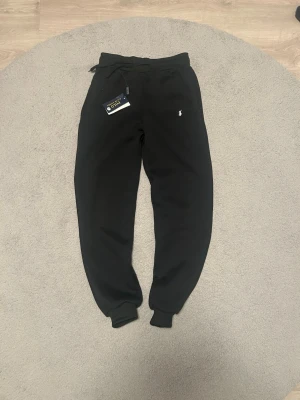 Svarta mjukisbyxor från Polo Ralph Lauren - Svarta mjukisbyxor i väldigt fint skick, endast använda 2 gånger. Inga fläckar eller skador. Längd cirka 97 cm och midjan cirka 39 cm . Jag är aktiv 24/7 och svarar snabbt på meddelanden. Fraktar samma dag eller senast nästa dag. Hör gärna av dig via frågor om du undrar något, annars är det bara att köpa direkt.✅📦🚛