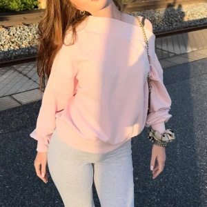 Ljusrosa offshoulder sweatshirt - Säljer en ljusrosa sweatshirt med offshoulder-design och långa ärmar. Tröjan har en relaxed passform och bred mudd i nederkant och vid ärmslut. Perfekt för en chill och trendig look.