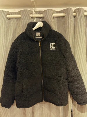 Svart teddyjacka från Karl Kani M - Galet mysig svart teddyjacka från Karl Kani i storlek M. Men passar L! Jackan har hög lurvig krage, guldfärgad dragkedja och snygg broderad logga på bröstet. Tillverkad i fluffigt teddy-material. Perfekt för kalla dagar när du vill vara både varm och stilren. Ordinariepris - 1595 kr!!