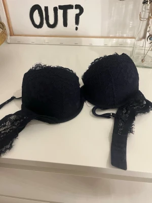 Mörkblå spets-bh med vadderade kupor - Säljer en mörkblå bh med vadderade kupor och fina spetsdetaljer. Axelbanden är justerbara och sidorna har transparent spets som ger en snygg look. Perfekt för dig som gillar en klassisk men ändå trendig stil. Tar emot andra priser