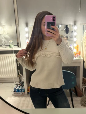 Vit stickad tröja med volang från Zara - Superfin vit stickad tröja från Zara med volangdetalj över bröstet och längs ärmarna. Tröjan har rund halsringning, ribbade muddar och är långärmad. Perfekt för kalla dagar och passar snyggt till allt!❣️Passar någon som har S eller XS
