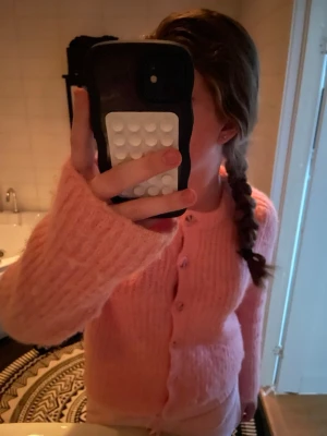 Rosa kofta från Vero Moda - Mysig rosa kofta från Vero Moda i stickad kvalitet. Koftan har långa ärmar, ribbad struktur och knäpps med matchande knappar framtill. Perfekt för lager på lager och ger en söt vibe till din outfit. Säljs då den bara har hängt i min garderob sedan jag köpte den. 