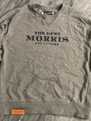 Grå Morris sweatshirt   - Grå sweatshirt från Morris Division med tryck. Perfekt för en chill och stilren look. Storlek S men passar även M. Skick 8/10. Inga defekter eller hål.