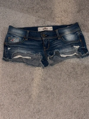 Lågmidjade jeansshorts från Hollister - Säljer ett par blå jeansshorts från Hollister med låg midja och slitna detaljer. Shortsen är väldigt bekväma och ser väldigt snyggt ut på. Perfekta till sommaren och riktigt snygga. Dom är i storlek w25, dom motsvarar typ storlek 34