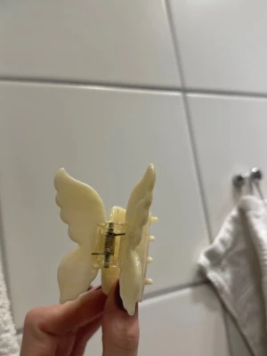 Hårklämma  -  en hårklämma i form av en fjäril i ljus vit färg, 