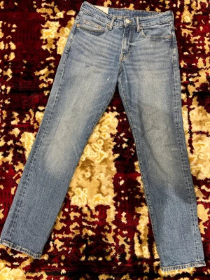 Straight fit jeans från H&M, 29/32 - Säljer ett par klassiska blå jeans från H&M i straight regular fit. Modellen har raka ben, fem fickor och gul kontrastsöm. Jeansen är tillverkade i bomull och har en tidlös blå tvätt som passar till allt.