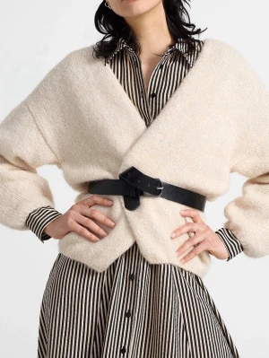 Beige omlott kofta med bälte - Säljer en supermjuk och fluffig beige omlott kofta med lång ärm. Koftan är stickad och har en oversized passform, perfekt att bära med bälte i midjan för en trendig look. Passar grymt till både skjorta och klänning.