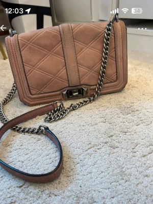 Beige quiltad axelväska Rebecca Minkoff - Säljer en snygg axelväska från Rebecca Minkoff med quiltad design och grov silverfärgad kedja. Väskan har rektangulär form, lock med metallspänne och insida med dragkedjefack. 25x15x10