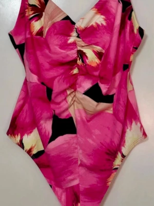 Blommig string body  - Säljer en färgstark string body  med stort blommigt mönster i rosa, beige, svart och gult. Materialet känns mjukt och stretchigt, perfekt för sommarens alla tillfällen. Snygg passform som framhäver midjan.