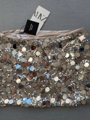 Glittrig paljettkjol från Zara - Säljer en superglittrig kortkjol från Zara, täckt med stora och små paljetter i silverton. Kjolen har en tight passform och är perfekt för att sticka ut på festen. Materialet är syntet och kjolen har en lyxig känsla med sin skimrande yta. Skriv vid frågor!❤️