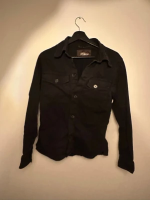 Svart overshirt från Oscar Jacobson - Hejsan’ jag säljer nu denna rikgit feta overshirt ifrån Oscar Jacobsson! Den ör i bra skick och är i storlek xs-S! Har tyvär ej kvitto men självklart äkta! Hör av er om ni har frågor!😁