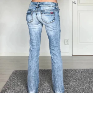 Replay bootcut jeans ljusblå lågmidja - Säljer ett par ljusblå Replay jeans med låg midja och bootcut-snitt. Jeansen har klassiska fem fickor, snygga slitningar och detaljerade sömmar. Materialet är jeans med en mjuk känsla och passformen är loose. Perfekt för dig som gillar retrovibe och cool stil.