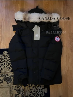 Canada Goose Wyndham Parka Red Label  - ❤️ Canada Goose Wyndham Parka Red Label – Svart (M) ❤️ Exklusiv och mycket varm vinterjacka från Canada Goose i Red Label-utförande med röd emblem och stilren premiumdesign. Mycket fint skick och redo för att skickas ut! Perfekt för nordiskt klimat med tjock dunfyllning, skyddande huva och djupa dragkedjefickor. Notera tagg avklipt. En lyxig och praktisk vinterfavorit.  📦 Snabb leverans – skickas samma dag 📩 (såvida inga hindr.) Skriv vid intresse
